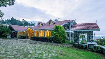 A traditional house with a stone facade, multiple chimneys, and a paved courtyard.