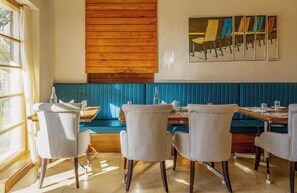 A restaurant interior with wooden paneling, a blue booth seating area, and a dining table with chairs.