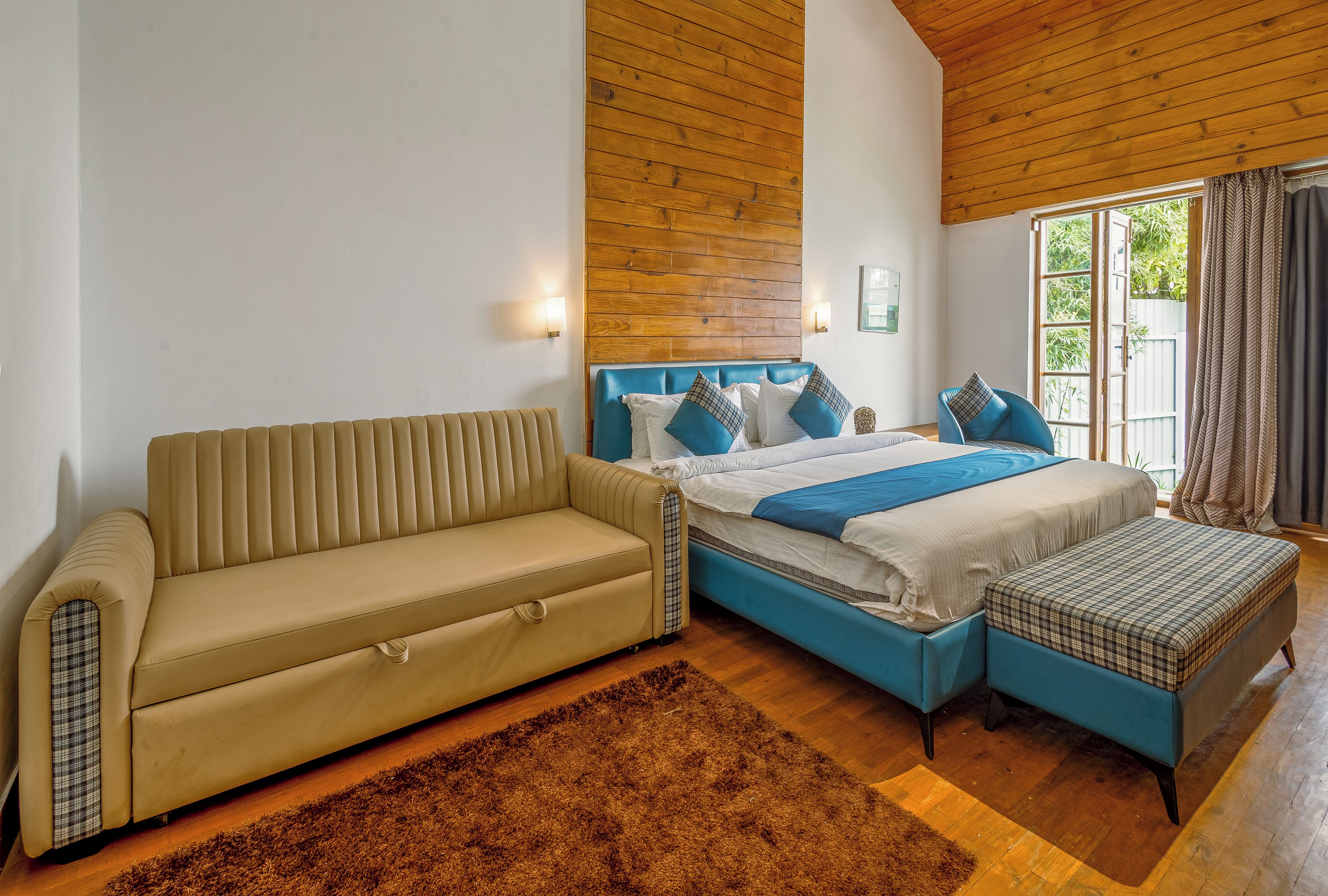 A bedroom with a bed, a sofa, and a window with curtains.