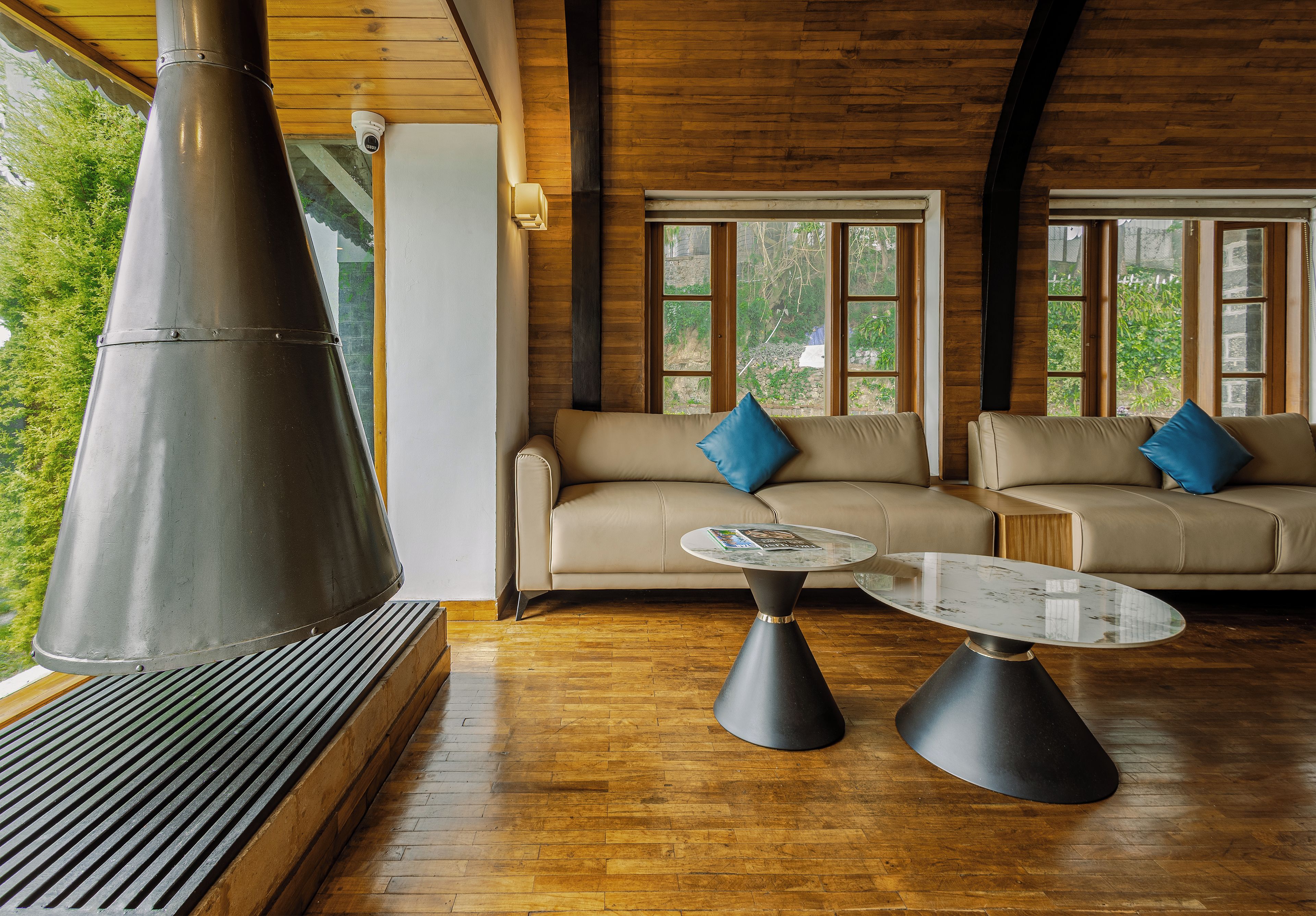 A modern interior with a large chimney, two sofas with blue cushions, and a glass coffee table.