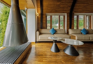 A modern interior with a large chimney, two sofas with blue cushions, and a glass coffee table. - The Mainland Resorts Kodaikanal (Kodaikanal)