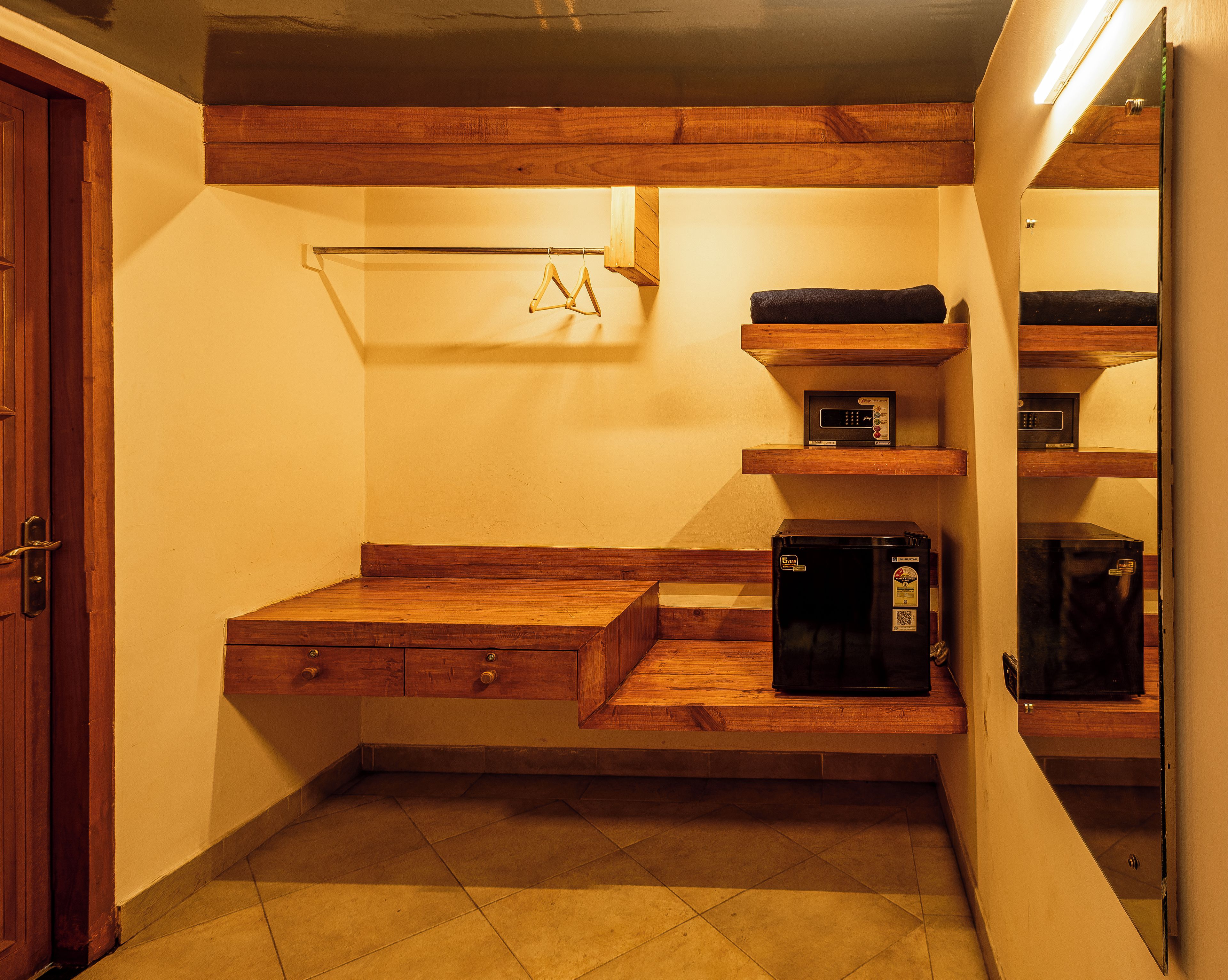 A compact kitchen with wooden cabinetry, a built-in microwave, and a small refrigerator.