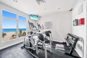 A fitness center with cardio machines, dumbbells, and a TV screen. - Seaside Serenity/Corner Unit/Best Gulf View (Panama City Beach)