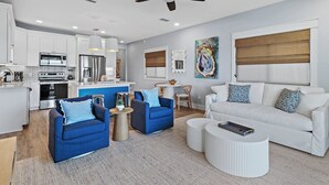 A modern living room with a white sofa, blue armchairs, and a white coffee table.