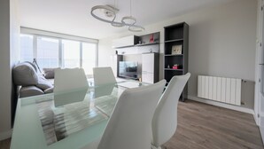 Una cocina moderna con una mesa de vidrio, sillas blancas y un horno empotrado.