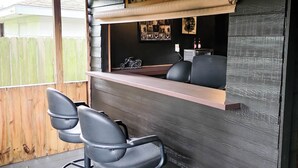 Angolo bar con un bancone in legno, due sgabelli da bar neri e un cartello con la scritta 'OUR BAR'.