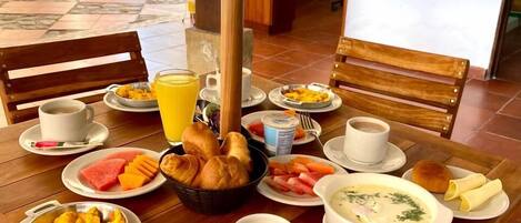 Una mesa de desayuno con diversos platos, una taza de café y un vaso de jugo.