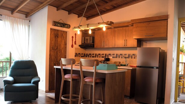 Eine Küche mit Holzschränken, einem Kühlschrank und einer Bar mit Barhocker.