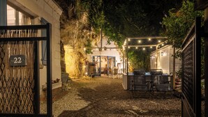 Un patio con muro de piedra, un letrero con el número 22, asientos al aire libre y guirnaldas de luces.