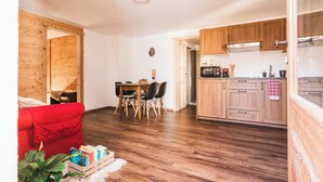 A compact living space with a dining area, a kitchenette, and a red sofa.