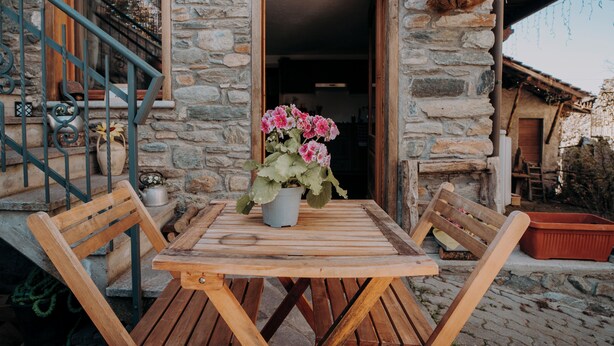 A stone building with a wooden table and chairs outside.