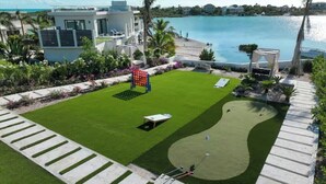 Um campo de golfe bem cuidado, com putting green, bunker de areia e lago.