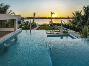 Ein Swimmingpool mit Sonnenuntergangsblick, umgeben von Palmen und einem gepflegten Rasen.
