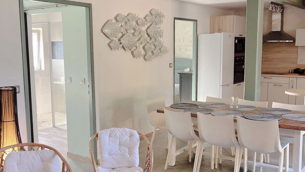 Uma cozinha moderna com armários brancos, bancada de madeira e forno embutido.