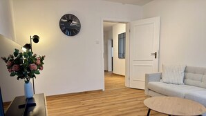 Un salon moderne avec une horloge murale ronde, un canapé, une table basse et un vase rempli de fleurs.