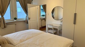 Une chambre à coucher avec un lit, une table de chevet, un miroir et une armoire.