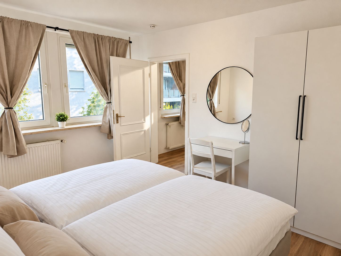 A bedroom with two beds, a bedside table, a mirror, and a wardrobe.