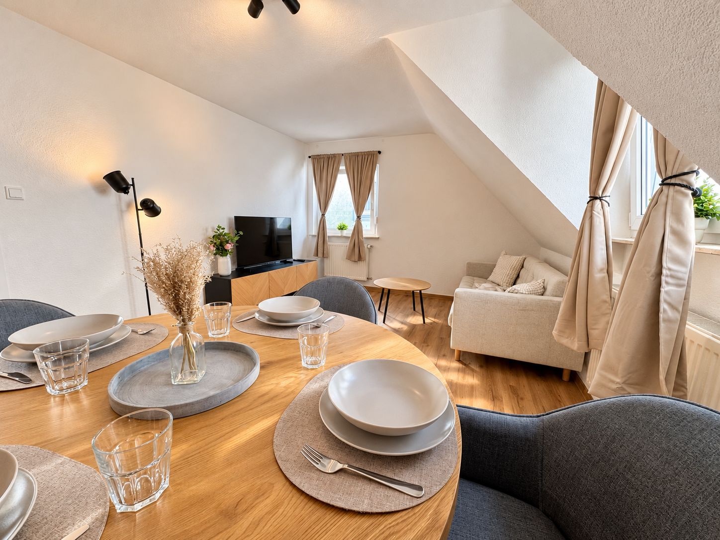 A modern living room with a dining area, a flat-screen TV, and a cozy sofa.