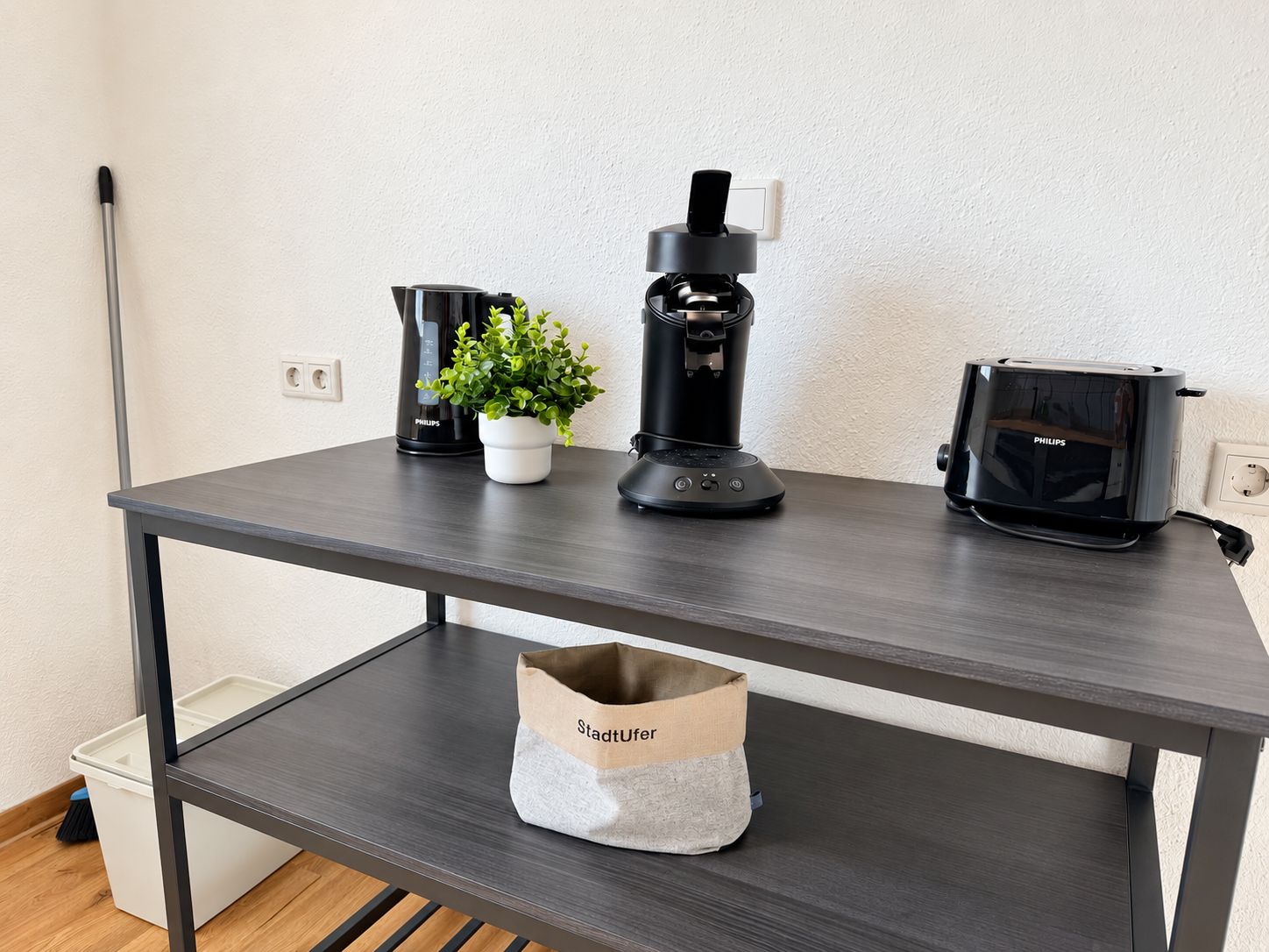 A modern kitchen with a coffee maker, a blender, and a toaster on a dark wooden table.