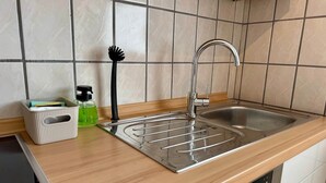 Una cocina con un lavamanos de acero inoxidable, una encimera de madera y un escurreplatos.