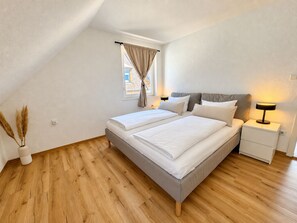 A bedroom with a bed, bedside tables, a window with curtains, and a lamp. - StadtUfer Apartment - Prime Location & Close to the Lake (Friedrichshafen)