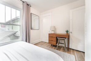 A bedroom with a bed, a wooden desk, a chair, a lamp, a globe, and a window with curtains. - Cozy 3BR Home in Bates-Hendricks (Indianapolis)