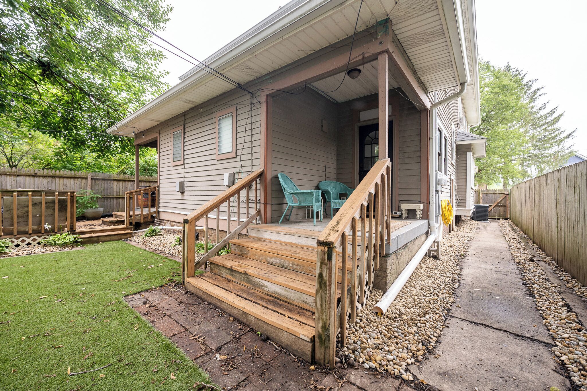A house with a wooden deck, a covered porch, and a small front yard.
