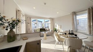 Una habitación moderna y luminosa con comedor, sofá y vistas al exterior.