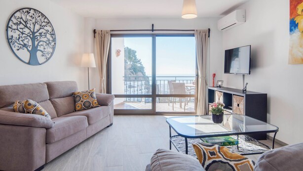 Un soggiorno moderno con un divano, un tavolino in vetro e vista sul balcone.