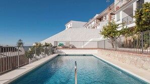 Una piscina con una scala in metallo, circondata da un muro in pietra e una recinzione metallica.