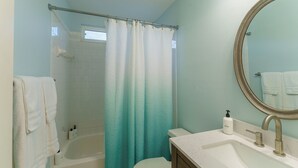 Ein Badezimmer mit einer Badewanne, einer Duschkabine, einem Waschbecken inklusive Spiegel und einer Toilette.