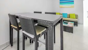 Ein Essbereich mit Tisch und Stühlen, eine Couch mit Kissen und eine Wand mit einem Gemälde.