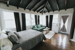 Une chambre à coucher avec un lit, un canapé vert, une table basse et une commode blanche.