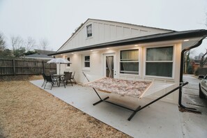 Une maison dotée d’un patio couvert, d’un hamac et d’une table avec des chaises.
