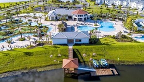 Oversigtsbillede af et resort med flere swimmingpools, en hovedbygning og en dock med kajakker.