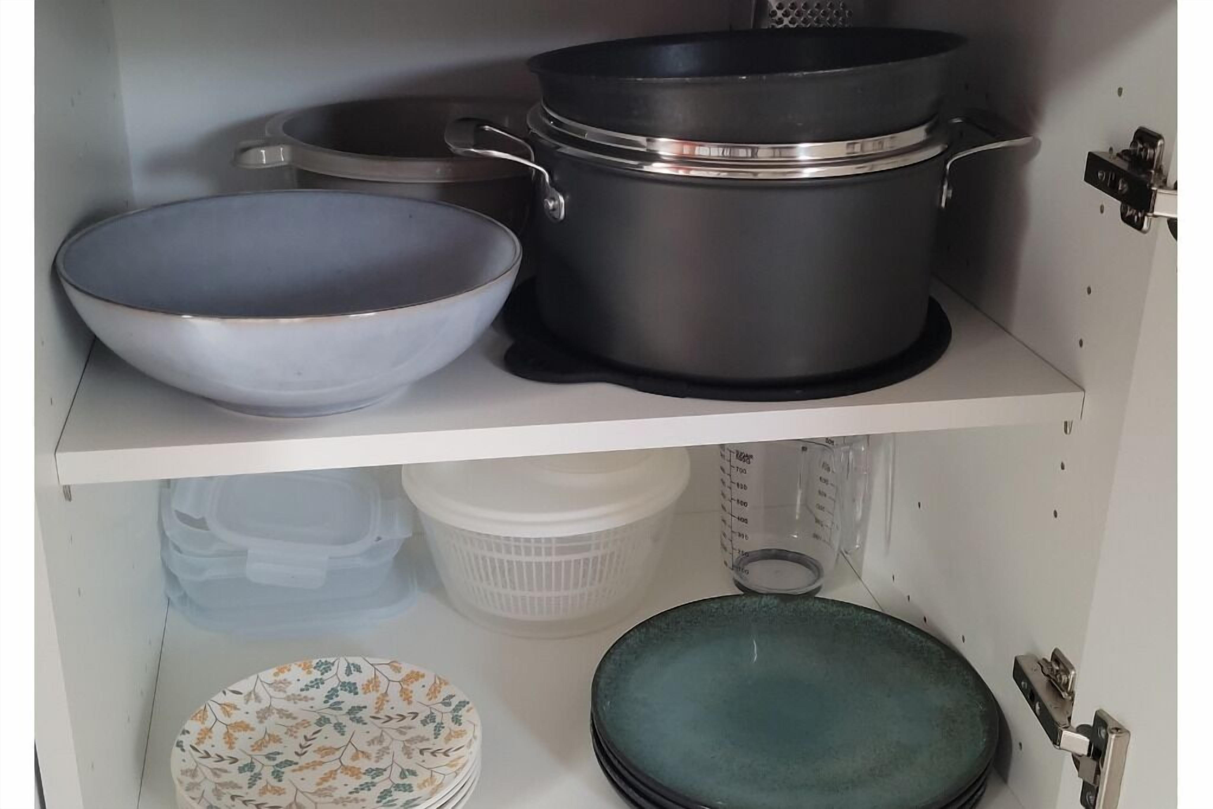 A kitchen shelf with cookware, including a large pot, a smaller pot, and a bowl.