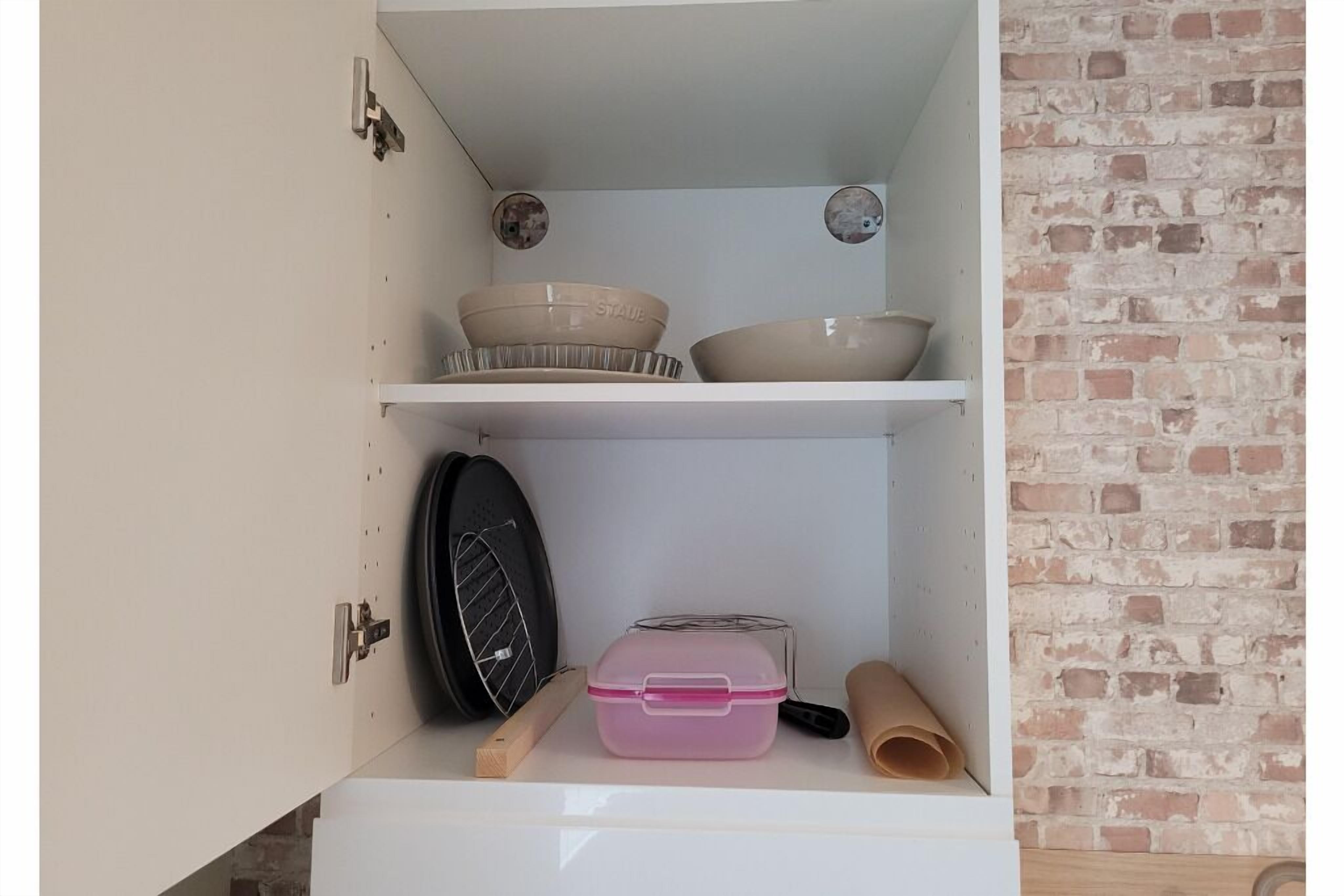 Un armario de cocina con repisas que contienen utensilios de cocina y un contenedor de almacenamiento.