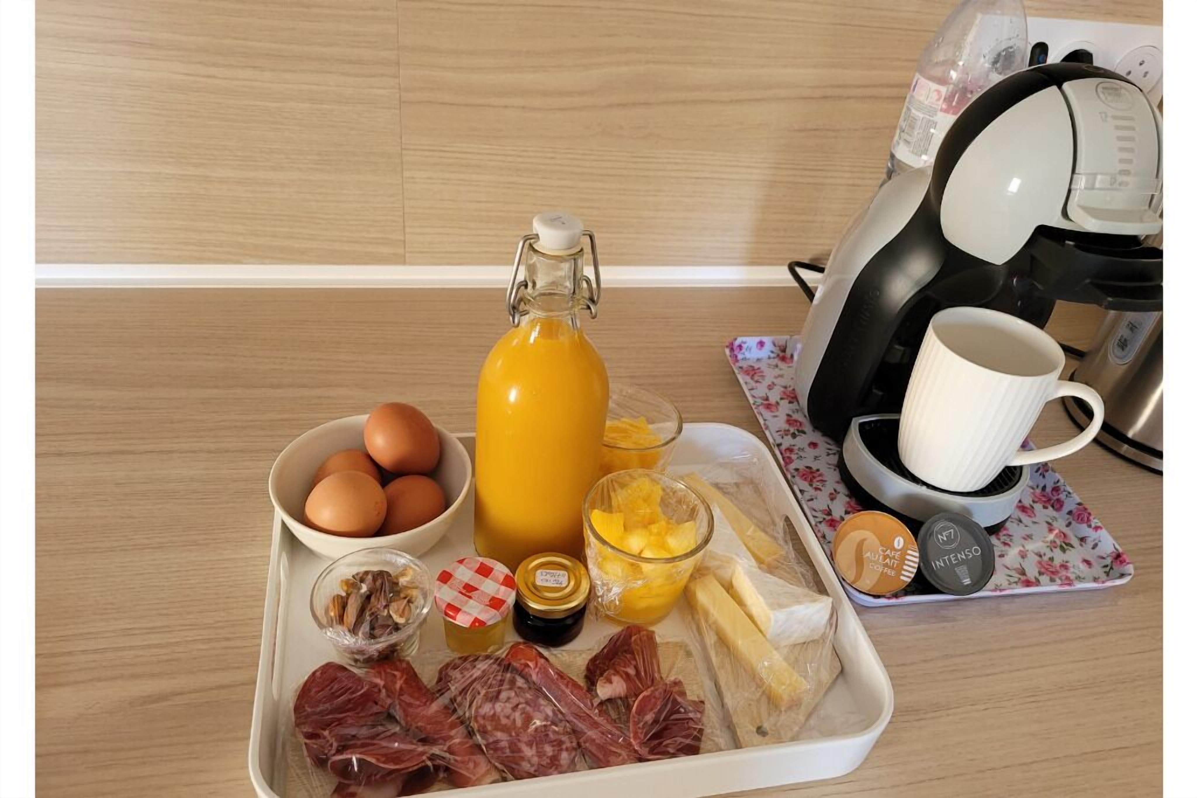 Un vassoio per la colazione con uova, succo d'arancia, formaggio, prosciutto e cialde per il caffè.