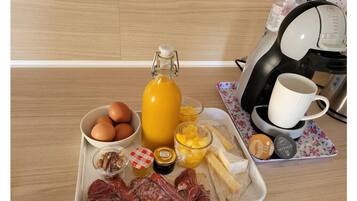Un vassoio per la colazione con uova, succo d'arancia, formaggio, prosciutto e cialde per il caffè.