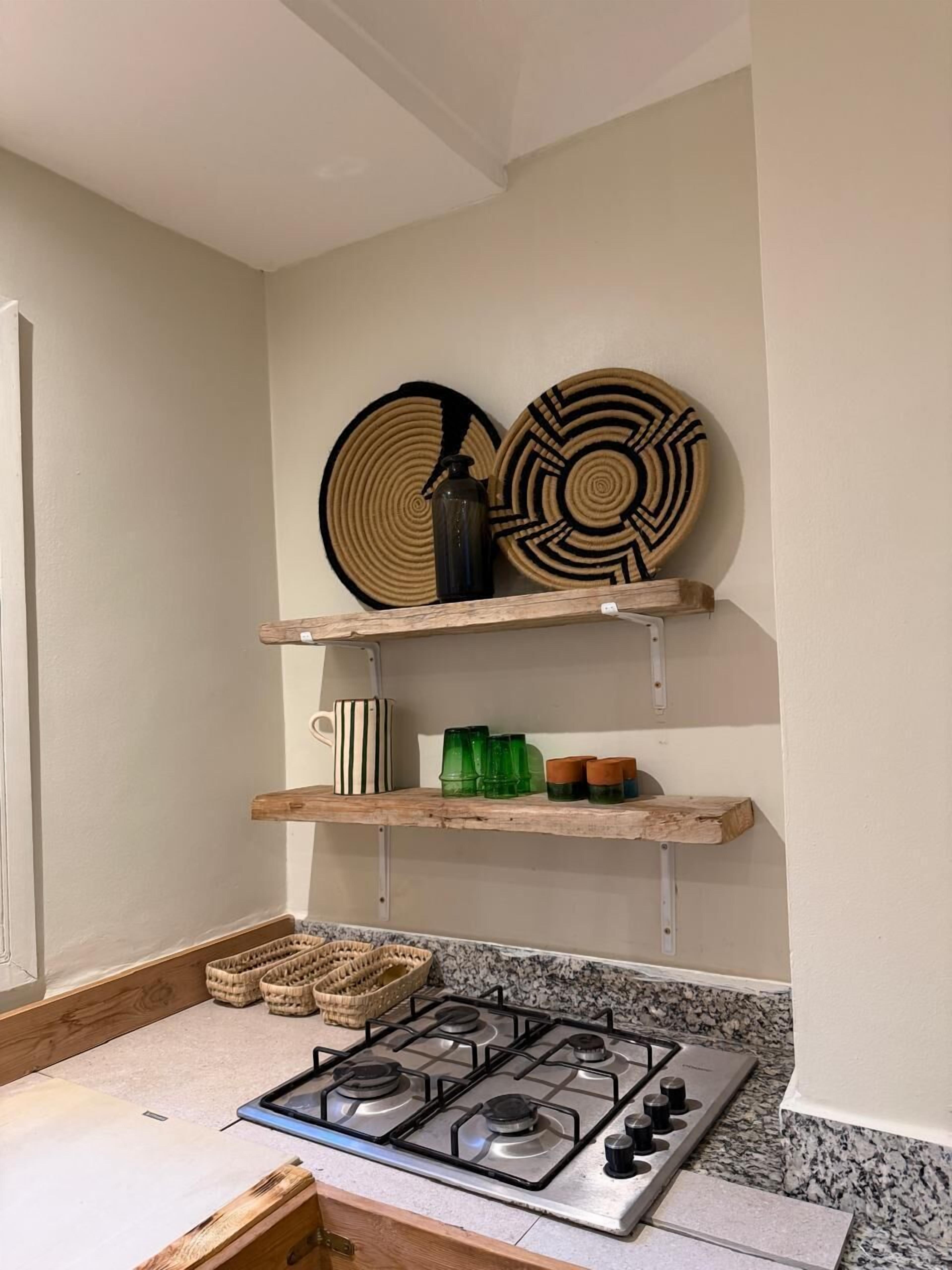 Una cocina con estufa a gas, repisas de madera y platos decorativos.