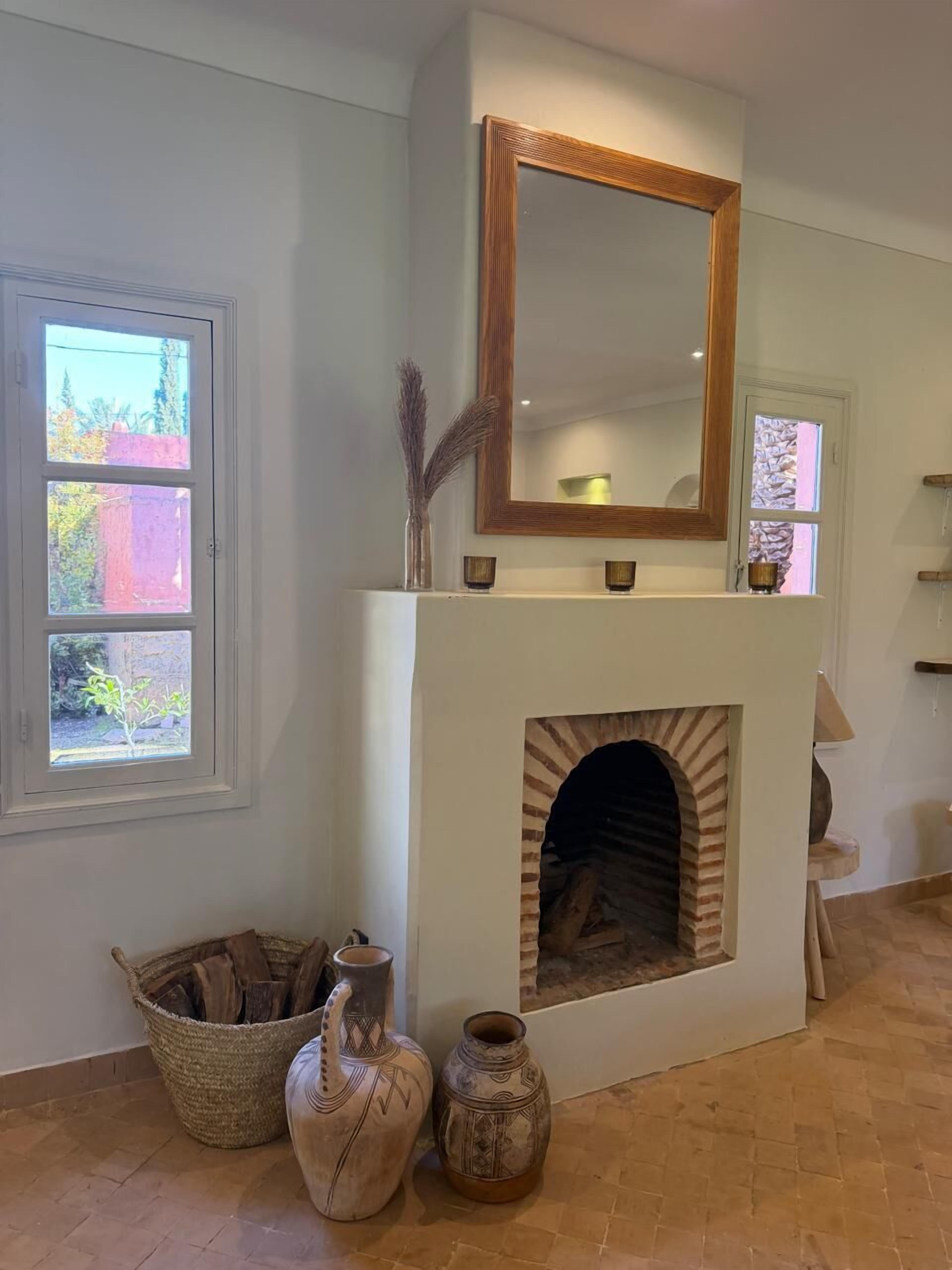 A room with a fireplace, a large mirror, and a window.