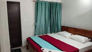 Une chambre à coucher avec un lit, des rideaux, une tête de lit en bois et un appareil de climatisation.