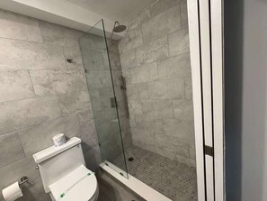 Une salle de bain avec une douche à parois de verre, des toilettes et un lavabo.