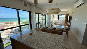 Et moderne hotelværelse med et stort vindue, der giver udsigt over stranden og havet.