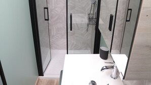 A modern bathroom with a glass-enclosed shower, a white sink with a mirror, and a wooden floor. - L'Atelier des rêves, air-conditioned, Dijon center (Dijon)