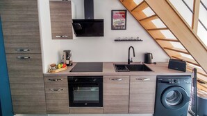 A compact kitchen with a built-in oven, a washing machine, and a coffee maker. - L'Atelier des rêves, air-conditioned, Dijon center (Dijon)
