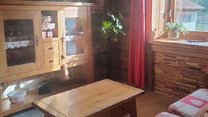 A rustic wooden room with a wooden table, a cushioned bench, a cabinet with glass doors, and a window with a view of trees. - Chalet les étoiles des Alpes close to ski resorts (Saint-Jean-d'Aulps)