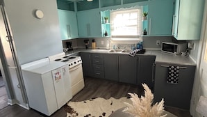 Une cuisine moderne avec des armoires de couleur turquoise, un fourneau blanc et un ventilateur de plafond.
