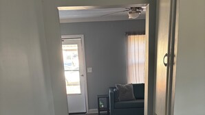 Un couloir mène à un espace de vie comprenant un canapé et une petite table.
