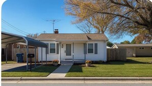 Une maison de plain-pied avec un porche à l’avant, un garage et une allée couverte.